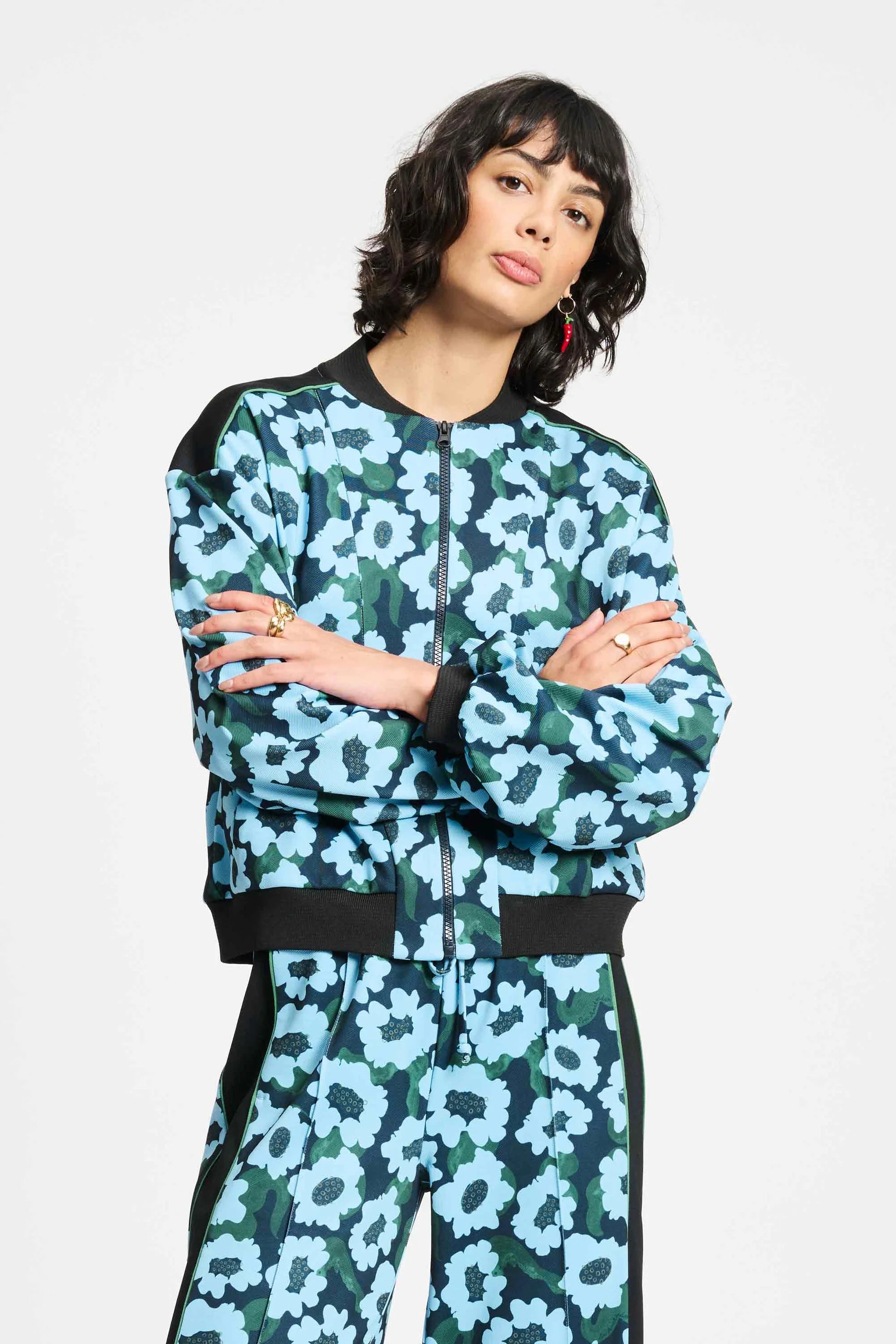 Woman wearing a blue and green floral bomber jacket and matching pants on a white background
