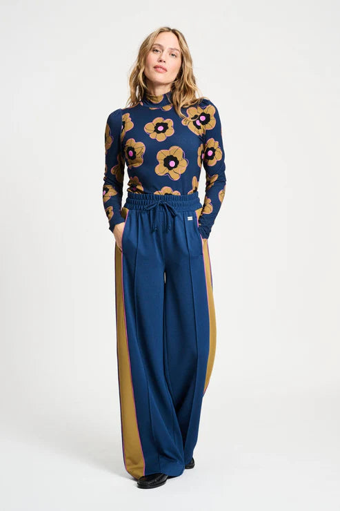 Woman wearing a floral top and wide-leg pants on a white background