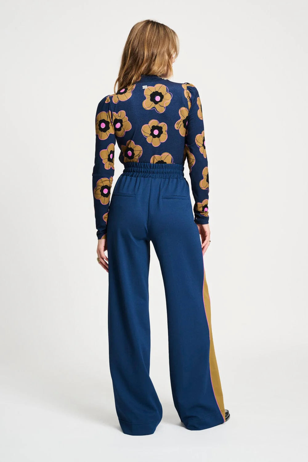 Person wearing a blue floral top and high-waisted pants on a white background
