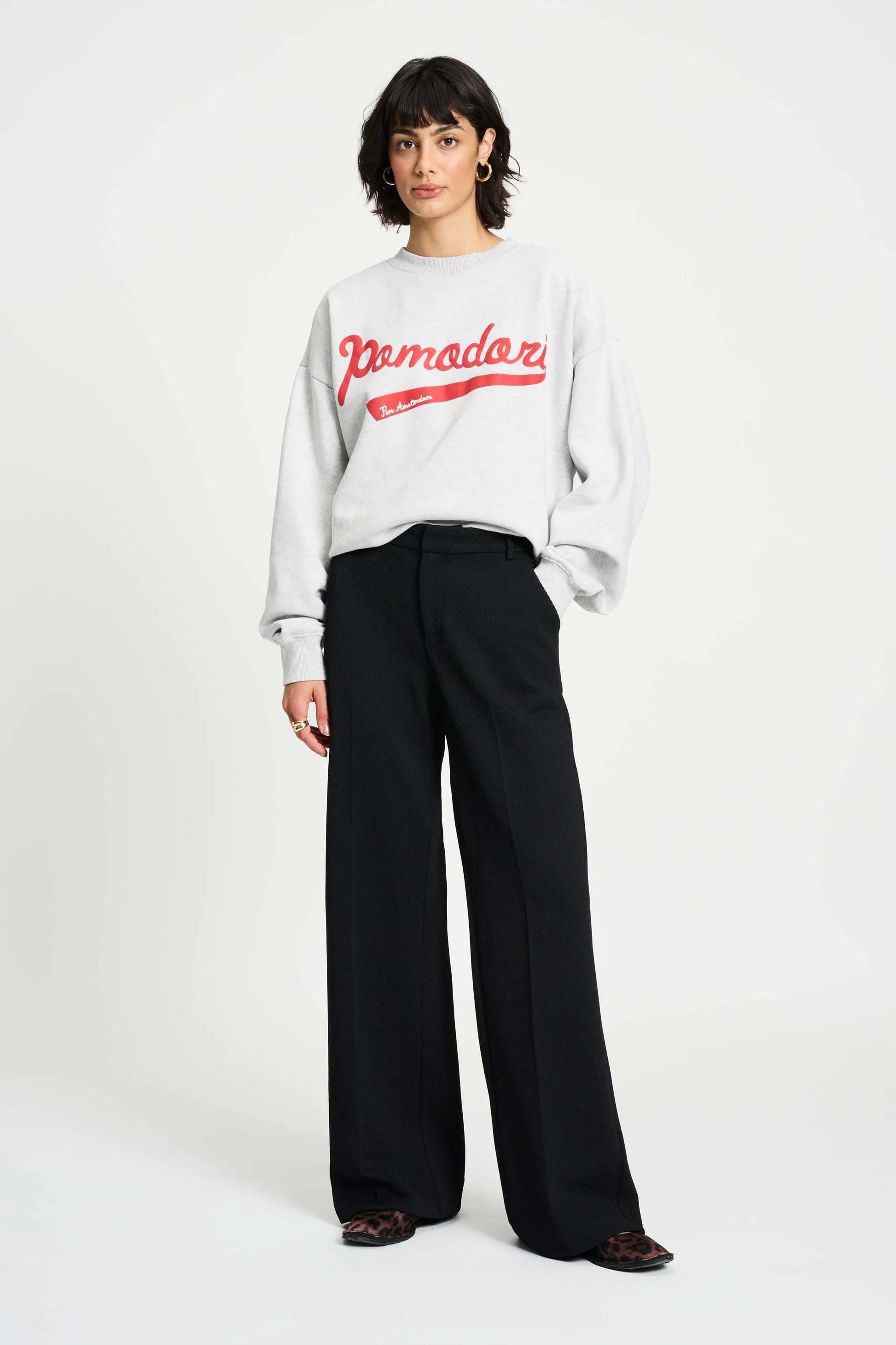 Woman wearing a white sweatshirt with red text and black pants on a white background