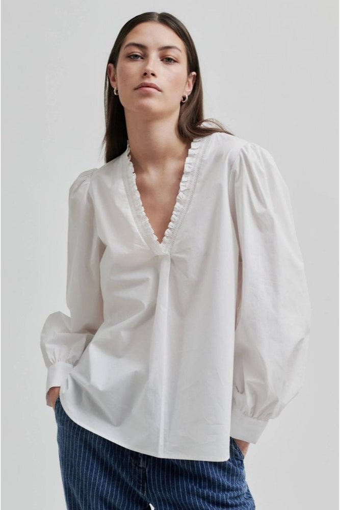 White long sleeve blouse with v neckline and frill detail. 