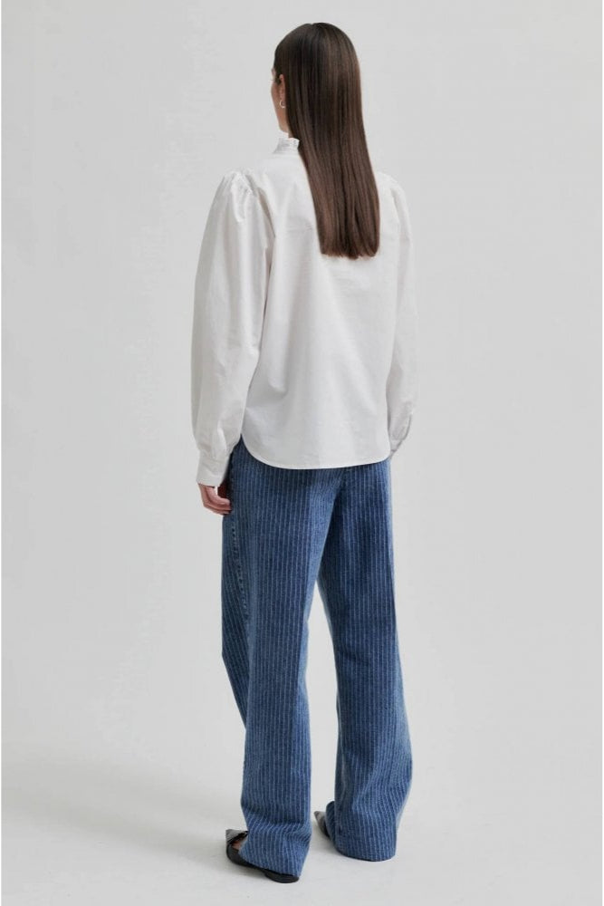 White long sleeve blouse with v neckline and frill detail. 