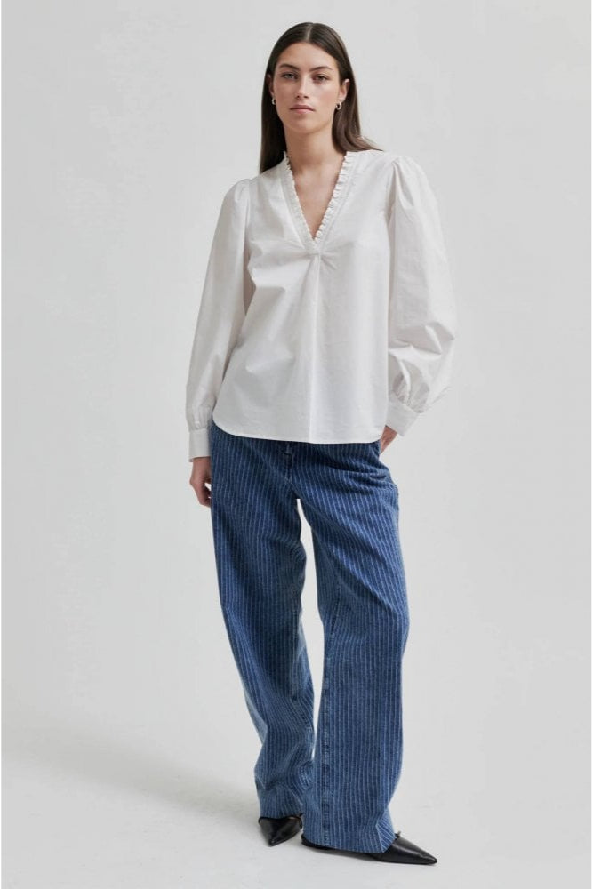 White long sleeve blouse with v neckline and frill detail. 