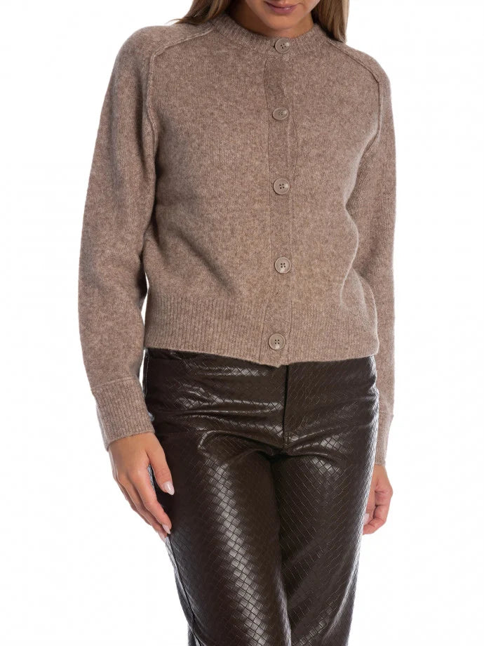 Person wearing a brown cardigan and shiny brown pants on a white background
