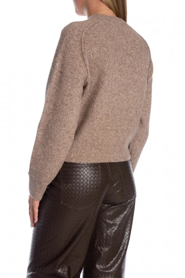 Person wearing a brown sweater and dark pants on a white background