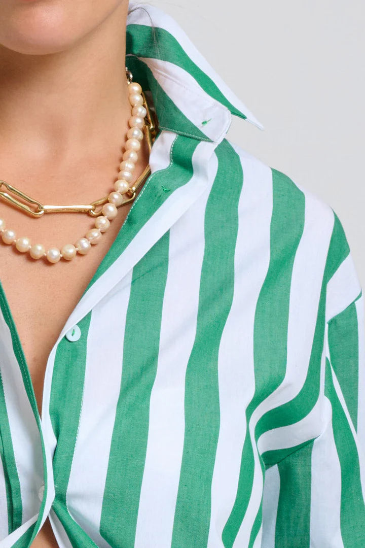 Green and white striped shirt with pearl necklace on a plain background