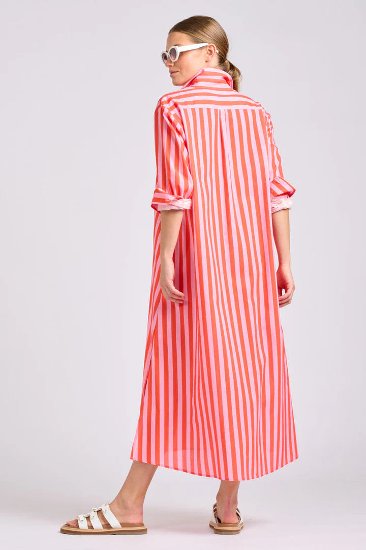 Woman wearing a papaya and light pink striped maxi shirt dress on a plain background